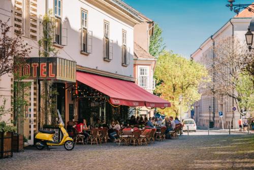 a street scene with a couple of tables and umbrellas at BALTAZÁR Boutique Hotel by Zsidai Hotels at Buda Castle in Budapest
