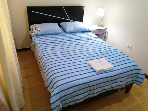 a bedroom with a bed with a blue and white striped comforter at YLLARICH in Trujillo