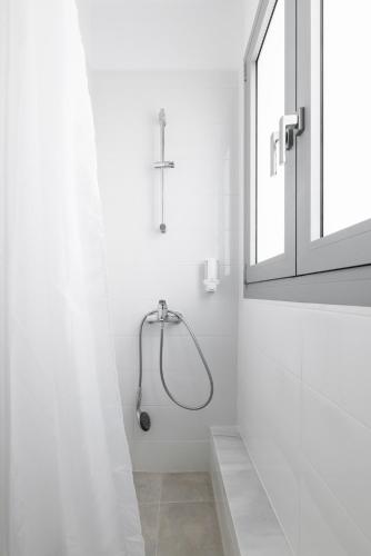 a shower in a white bathroom with a window at Boho Rooms in Thessaloniki