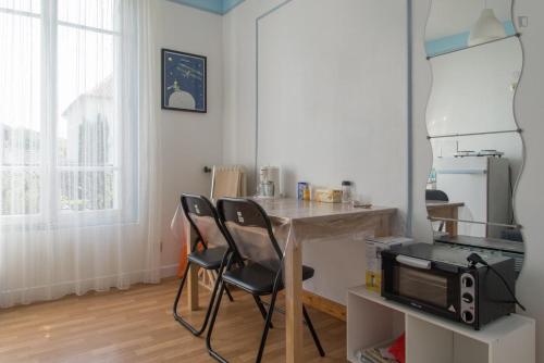 cocina con mesa, sillas y microondas en Chambre du Petit Prince, en Chaville