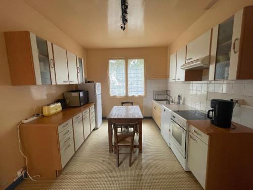 une cuisine avec des placards blancs et une petite table. dans l'établissement Villa MarieAnne, à Mimizan