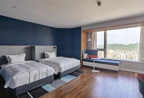 a bedroom with two beds and a blue wall at Holiday Inn Express Zhoushan Dinghai by IHG in Zhoushan