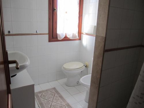ein weißes Bad mit einem WC und einem Waschbecken in der Unterkunft casa mirice in residence con piscina ,wifi,climatizzatore vicino al mare in Aglientu