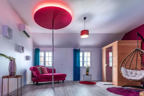 a living room with a red chair and a swing at Suite L'echappee - Maison romantique - SPA & Sauna Privatif- Pole Dance - Lit rond avec miroir au plafond in Pézarches