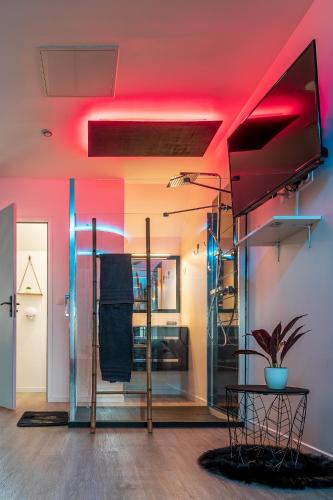 a room with a red ceiling and a table with a television at Suite L'echappee - Maison romantique - SPA & Sauna Privatif- Pole Dance - Lit rond avec miroir au plafond in Pézarches