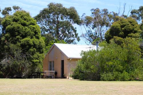 um pequeno edifício com um banco num campo em Bells Beach Cottages - Pet friendly cottage with wood heater em Torquay