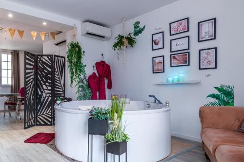 a living room with a tub and a couch at Suite L'echappee - Maison romantique - SPA & Sauna Privatif- Pole Dance - Lit rond avec miroir au plafond in Pézarches