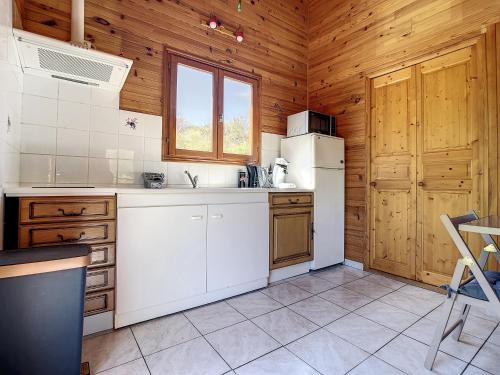 a kitchen with a white refrigerator and wooden walls at Chalet grand jardin, au calme, proche commerces in La Canourgue