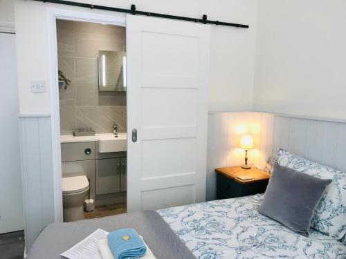 1 dormitorio con 1 cama y baño con lavamanos en Arden House en Arundel