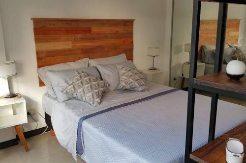 Schlafzimmer mit einem Bett mit einem Kopfteil aus Holz und Kissen in der Unterkunft Gurruchaga Suites free parking Movistar Outlet in Buenos Aires