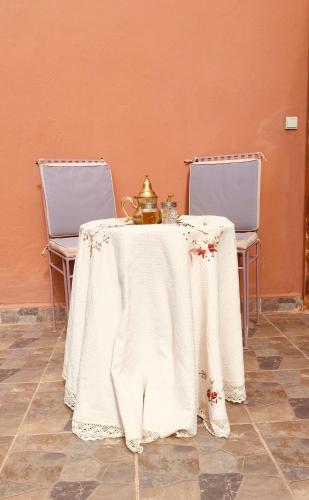 a table with a tea kettle on it with two chairs at Riad Nasma Souihla in Marrakech