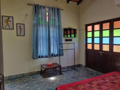 a room with a bed and a table and a window at Villa Agastya in Betalbatim