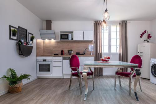kuchnia ze stołem i 2 różowymi krzesłami w obiekcie Suite L'echappee - Maison romantique - SPA & Sauna Privatif- Pole Dance - Lit rond avec miroir au plafond w mieście Pézarches