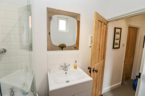 a bathroom with a sink and a shower and a mirror at Anchor Cottage in Whitby