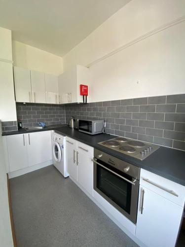 a kitchen with a stove and a washer and dryer at Lovely 1 bedroom apartment in Norwich in Norwich