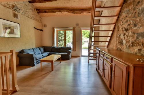 a living room with a couch and a staircase at Gîtes du Pont de Calmel in Rieussec
