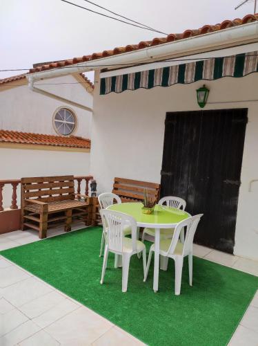 a patio with a table and chairs on a green rug at Lemos family beach house in Nazaré