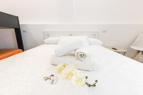 a white bed with towels and flowers on it at La Gemma del Salento Rooms&Apartments in Racale