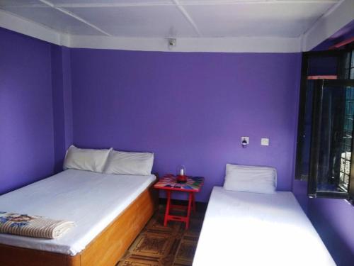 2 camas en una habitación con una mesa roja en City View Home Stay en Tānsen
