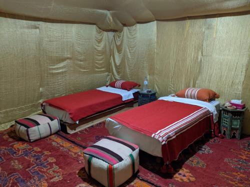 a room with two beds and two ottomans at Sahara Desert Experience camp in Merzouga