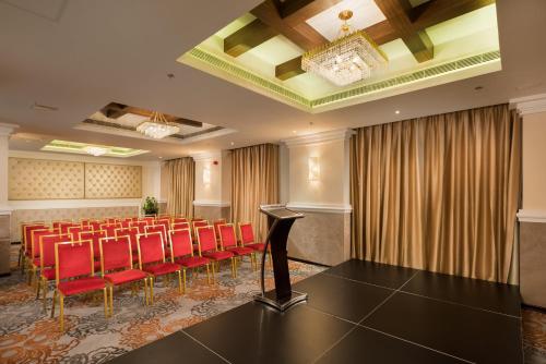 a conference room with red chairs and a podium at Centara Muscat Hotel Oman in Muscat
