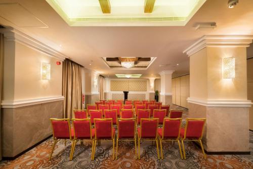 a conference room with red chairs and a podium at Centara Muscat Hotel Oman in Muscat