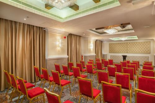 a conference room with red chairs and a podium at Centara Muscat Hotel Oman in Muscat