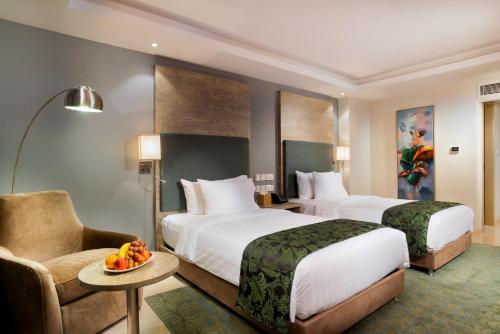 a hotel room with two beds and a chair at Centara Muscat Hotel Oman in Muscat