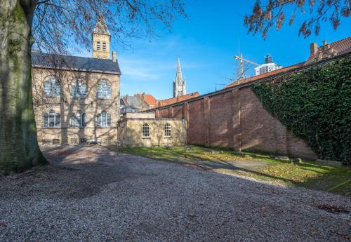 an old brick building with a clock tower and a tree at LOFT d'O in Ypres