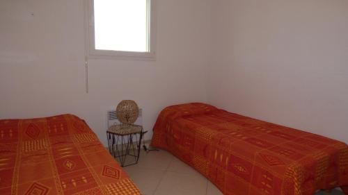 une chambre avec deux lits et une chaise et une fenêtre dans l'établissement Appartement T3 climatisé, Les Bastides de la Plage, Narbonne Plage, à Narbonne-Plage