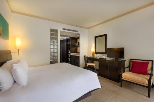 Schlafzimmer mit einem Bett, einem Schreibtisch und einem Stuhl in der Unterkunft Centara Kata Resort Phuket in Kata Beach