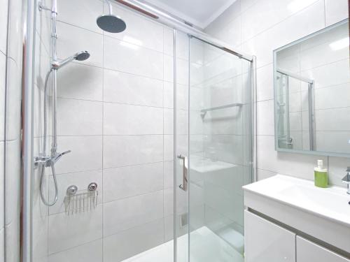 een witte badkamer met een douche en een wastafel bij Casa Rita - Close to the city centre within walking distance to the beaches in Lagos