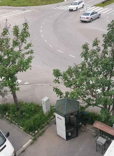 a trash can next to a road with a car at Apartment Luka in Podgorica