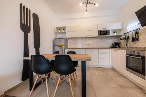 a kitchen with a wooden table and black chairs at Apartments Frgacic I in Baška