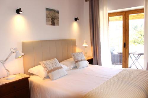 a bedroom with a bed with white sheets and a window at Quinta das Alfambras in Aljezur