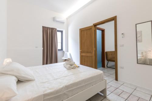 a bedroom with a large white bed with a stuffed animal on it at La Gemma del Salento Rooms&Apartments in Racale