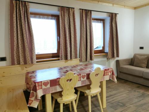 a kitchen with a table and two chairs and a couch at App Col di Lana - Agriturismo La Majon da Col in Colle Santa Lucia