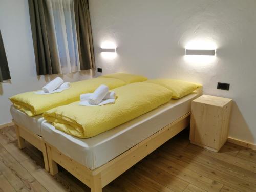 a bed with yellow sheets and white towels on it at App Col di Lana - Agriturismo La Majon da Col in Colle Santa Lucia