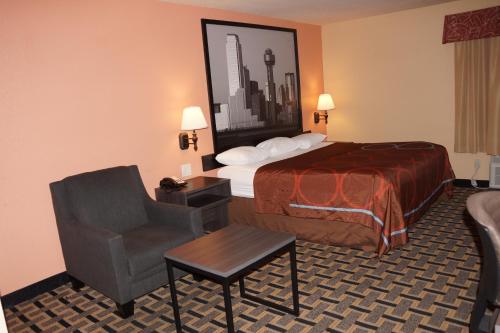 ファーマーズ・ブランチにあるSuper 8 by Wyndham Farmers Branch/North Dallasのベッドと椅子のあるホテルの部屋