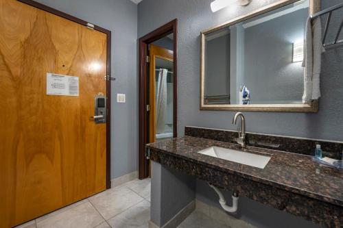 a bathroom with a sink and a mirror at Suburban Studios Lafayette in Lafayette