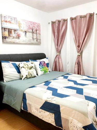 a bedroom with a bed with a blue and white comforter at One Oasis By Paseo de Corazon Residence in Cagayan de Oro