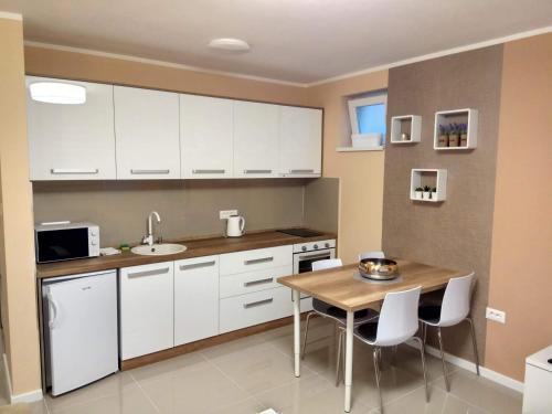 a kitchen with white cabinets and a wooden table at Apartment Cherry Gold in Zrenjanin