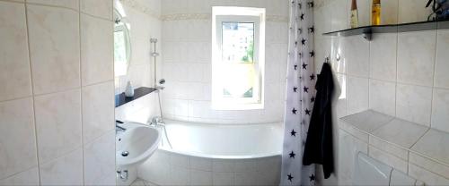 a white bathroom with a sink and a bath tub at Pension Rudolph Riesa in Riesa