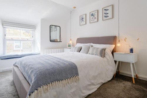 a white bedroom with a large bed and a window at Finest Retreats - Coral Cottage in Porthleven