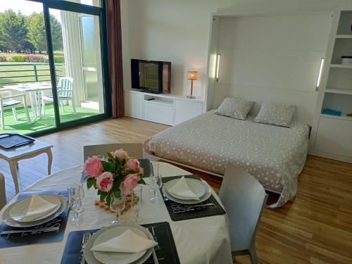 Un dormitorio con una cama y una mesa con flores. en Appartement de standing dans le Golf International de La Baule en Saint-André-des-Eaux