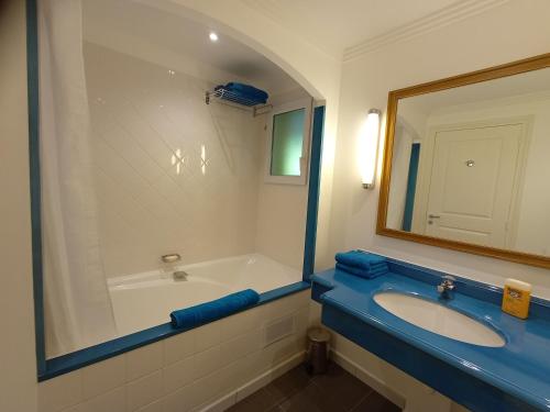 a bathroom with a tub and a sink and a mirror at Appartement de standing dans le Golf International de La Baule in Saint-André-des-Eaux