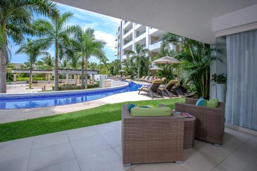 an outdoor patio with chairs and a swimming pool at Marival Distinct All-Suites & World Spa - Handwritten Collection in Nuevo Vallarta 