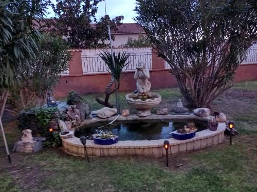 a garden with a fountain in the middle of a yard at Un Nid Douillet en bord de plage !! in Lucciana