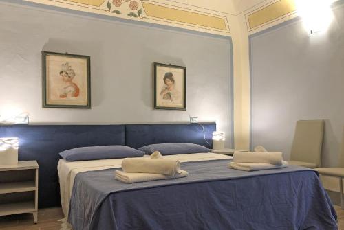 a bedroom with a blue bed with two pillows on it at Suite Apartment Castello in Volterra