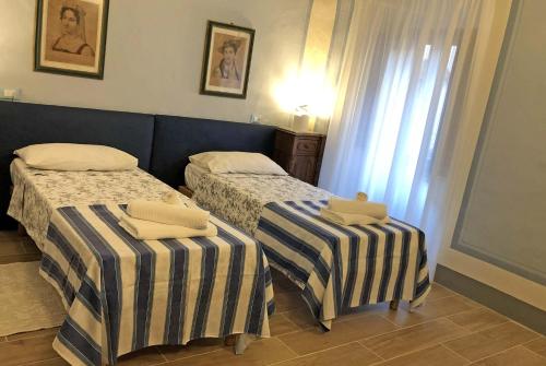 two beds in a small room with a window at Suite Apartment Castello in Volterra